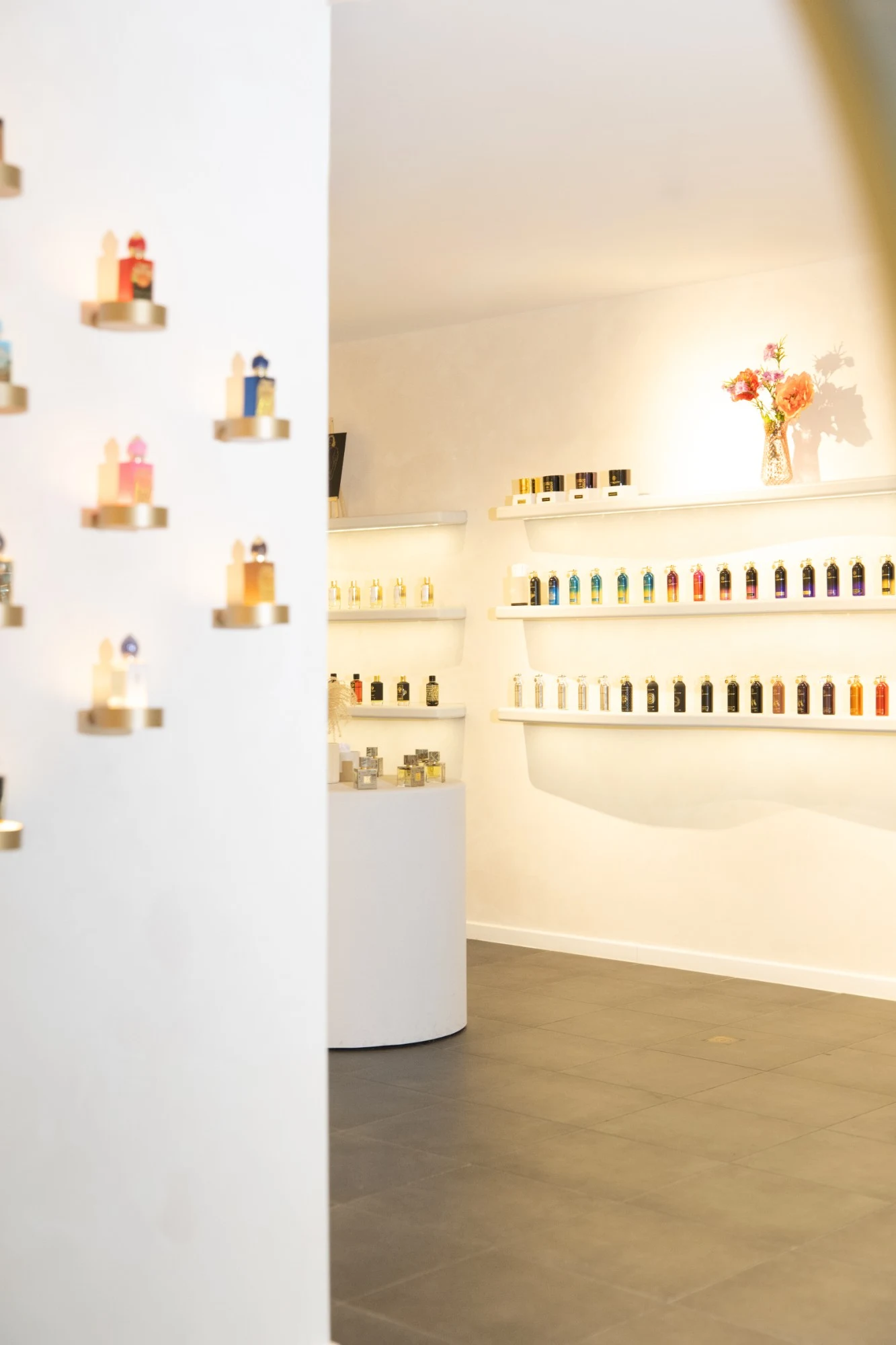 Binnen in Maison M&R: parfums op verlichte planken en gouden sokkels
